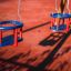 Double Baby Swing in un parco giochi con sedili rossi e blu su catene.