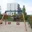 Double Baby Swing con struttura in legno e sedili rossi e blu in un parco giochi urbano