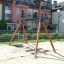 Double Swing in un parco giochi con edifici residenziali sullo sfondo.