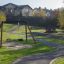 Struttura da gioco Double Swing con un pneumatico e un sedile tradizionale in un parco con vialetti e colori