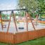 Attrezzature da gioco Double Swing in un'area giochi recintata con altre strutture da gioco visibili.