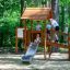 Galapagos wooden playhouse with slide e bambini che giocano all'aperto in un'area giochi nel bosco