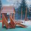 Tambora wooden playhouse with slide su un'area giochi all'aperto