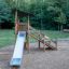 Elbrus wooden playhouse with slide in un parco giochi circondato da alberi