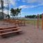 Attrezzature per fitness all'aperto e tavoli da picnic in un parco vicino a un lago.