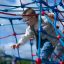Bambino che si arrampica su attrezzature da parco giochi Autan climbing net in una giornata di sole