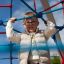 Bambino che si arrampica su attrezzature da parco giochi Autan climbing net in un ambiente all'aperto
