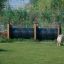 Due cani vicino a un Agility Tunnel in un'area erbosa recintata.