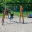 Bambini che giocano su un set di altalene Blackboard 156 cm in un parco giochi sabbioso.