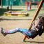 Ragazza che dondola su Twister w/ swing in un parco giochi