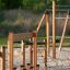 Percorso a ostacoli per parchi giochi in legno Trim trail con pali da arrampicata e corde su terreno sabbioso.