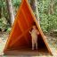 Bambino in piedi all'interno di Tipi Nature wooden house nel parco giochi in un ambiente boschivo