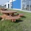 Round table & benches in un'area esterna erbosa vicino a un edificio moderno.