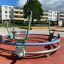 Bicycle merry-go-round in un parco giochi con edifici residenziali sullo sfondo.