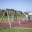 2+2 multiple swing installato in un parco giochi con pavimentazione in gomma e parete da arrampicata sullo sfondo