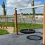 Altalena in legno Double Swing Robinia (BNS 90) in un parco giochi con sedile a pneumatico.