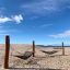 Double Hammock su una spiaggia sabbiosa con supporti in legno e un cielo azzurro limpido.