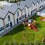 Tappeti di sicurezza in gomma in un'area giochi per bambini accanto a moderne case a schiera e a una piscina.