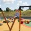 Bambino che gioca su un Bird Nest Single Swing (BNS 120 cm) in un parco giochi.