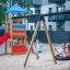 Bambini che giocano sull'altalena Bird Nest con torre (BNS 120 cm) con uno scivolo singolo in un parco giochi.