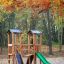 Set da gioco in legno per esterni Mini Play Modern Nature con scivolo in un bosco autunnale.