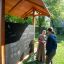Picnic Shelter w/ Blackboard struttura da gioco in legno all'aperto con lavagna e persone che interagiscono