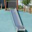 Scivolo Hill Slide h120 all'aperto su un dosso blu con prato verde