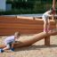 Bambini che giocano sulla trave di equilibrio in legno Ramp in un parco giochi all'aperto.