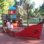 Bambini che giocano su una sabbiera a forma di nave in un parco.