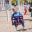 Bambino che gioca su Nature Double Swing in un parco giochi sabbioso.