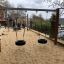Double swing installato in un parco giochi sabbioso.