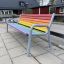Colourful bench con doghe in legno arcobaleno e struttura in metallo grigio nel parco giochi.
