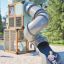 Box "Breeze" with a slide attrezzatura da parco giochi con un bambino che scivola lungo uno scivolo curvo argentato.