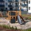 Moderno set da parco giochi in legno 'Climbing Kiosk Nature' nel cortile di un complesso residenziale.