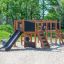 Bambini che giocano sulla struttura del parco giochi Romping Center Nature con scivoli e elementi da arrampicata all'aperto
