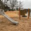 Slide in acciaio inox in un parco giochi all'aperto sabbioso vicino al lago.