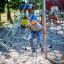 Bambino che scala su Powerclimber climbing net nel parco giochi.