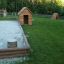 Sabbiere in legno in un parco giochi con erba e piccole casette.