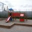 Parco giochi all'aperto con uno scivolo rosso e una torre.