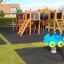 Attrezzatura da parco giochi in legno Square Play Nature con scivoli, scale e giochi a molla in un parco.