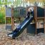 Bambini che giocano sullo scivolo del parco giochi Square Play Nature in una foresta autunnale.