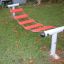Attrezzatura da parco giochi Bridge rossa e bianca sull'erba.