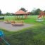 Set da parco giochi Firehouse con scivolo rosso e strutture in legno nel parco.