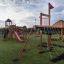 Struttura da parco giochi all'aperto Firehouse con scivoli, rete da arrampicata e casetta su un campo erboso, s