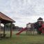Struttura da parco giochi Firehouse con scivoli rossi e strutture da arrampicata in legno in un parco.