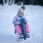 Bambino seduto su attrezzatura da parco giochi Yacht Swing rocking in un'area esterna innevata