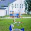 Yacht Swing rocking nell'area giochi con erba verde e edificio bianco sullo sfondo