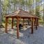 Riparo in legno Long Firehouse con tavoli da picnic e griglia in una foresta.