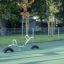 Altalena a bilico in un parco giochi con superficie verde circondata da alberi