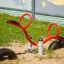 Attrezzatura da parco giochi rossa SeeSaw su terreno sabbioso con un murale sullo sfondo.